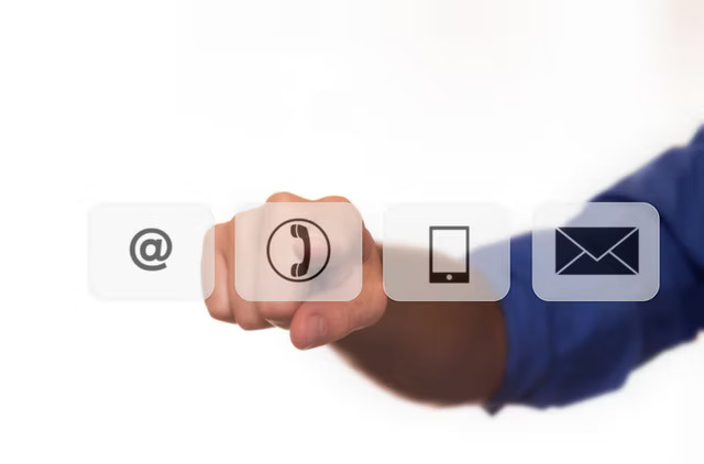 Hånd peger på ikoner: @, telefon, tablet, mail